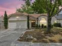 Charming single-story home at twilight featuring a two-car garage and arched window at 1345 Tindaro Dr, Apopka, FL 32703