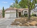 Charming single-story home featuring a two-car garage, arched window, and manicured landscaping at 1345 Tindaro Dr, Apopka, FL 32703