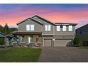 Charming two-story home with a well-manicured lawn and a three-car garage during a colorful sunset at 2017 Camden Loop, Davenport, FL 33837