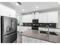 Modern kitchen featuring stainless steel appliances, a large island, stone accents, and dark backsplash at 2017 Camden Loop, Davenport, FL 33837