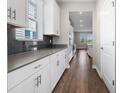 Long shot of kitchen featuring granite counters, stainless steel appliances, grey tile backsplash and wooden floors at 2017 Camden Loop, Davenport, FL 33837
