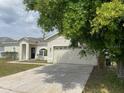 Inviting single-story home with a two-car garage, mature trees, and a well-kept lawn at 322 Ashburton Way, Kissimmee, FL 34758