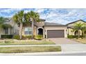 Beautifully landscaped front yard with palm trees, stone accents, and a brick driveway leading to a two-car garage at 333 Almansa St, Davenport, FL 33837