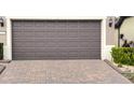 Close-up of a brown two-car garage door with decorative panels and a brick paver driveway at 333 Almansa St, Davenport, FL 33837