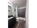 Bathroom showcasing a black vanity with a modern sink, a toilet, and a bathtub with a shower curtain at 377 Holly Berry Dr, Davenport, FL 33897