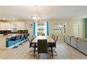 Dining area with a large wooden table, stylish chairs, modern light fixture, and views of the backyard at 581 Pebble Beach Dr, Davenport, FL 33896