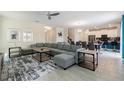 Open-concept living room features neutral walls, tile floors, contemporary decor, and a large gray sectional sofa at 581 Pebble Beach Dr, Davenport, FL 33896