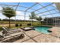 Screened-in pool and spa area with lounge chairs overlooking a well-maintained lawn and putting green at 581 Pebble Beach Dr, Davenport, FL 33896