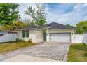 Inviting single-story home boasts a light-colored facade, solar panels, and a brick paver driveway at 7629 Marietta St, Orlando, FL 32807
