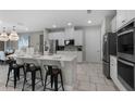 Modern kitchen with stainless steel appliances, quartz countertops, large island, and stylish black bar stools at 7665 Fairfax Dr, Kissimmee, FL 34747