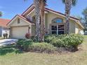 Beautiful single-story home with a terra cotta roof, two-car garage, lush landscaping and mature palm trees at 1102 Solana Cir, Davenport, FL 33897