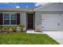 Close-up of a home's front entrance, showcasing a paneled door, manicured landscaping, and a two-car garage at 2705 Grandbury Grove Rd, Lakeland, FL 33811