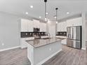 Modern kitchen with stainless steel appliances, white cabinetry, center island, and sleek countertops at 3038 Camden Way, Davenport, FL 33837