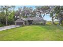 Single story home featuring a sprawling green lawn, mature trees, and a two-car garage at 420 Ketch Rd, St Cloud, FL 34771