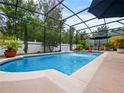 Inviting screened-in pool area with a fountain feature, patio furniture, and lush greenery at 572 Nogales Ct, Kissimmee, FL 34758