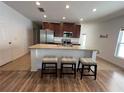 Well-lit open concept kitchen with stainless steel appliances and granite counters, plus seating at the island at 939 Anna Pl, Davenport, FL 33837