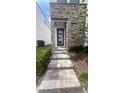 Close-up of a stone-accented home entrance with a paved walkway and manicured bushes at 236 Villa Domani Cir, Davenport, FL 33896