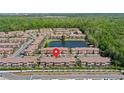 Aerial view of townhome community featuring lush landscaping, a central pond, and resort-style amenities at 2618 Roadster Ln, Kissimmee, FL 34746