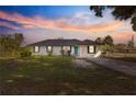 Beautiful single-story home features a modern front exterior with a manicured lawn under a colorful sunset at 1401 Nw 63Rd Pl, Ocala, FL 34475