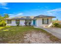 Inviting single-story home with a well-kept lawn, blue door, gray shutters, and a paved driveway under a sunny sky at 1401 Nw 63Rd Pl, Ocala, FL 34475