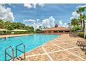 Outdoor pool with brick surround, clubhouse, lounge chairs, palm trees, and clear blue skies at 3341 Rodrick Cir, Orlando, FL 32824