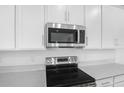 Contemporary kitchen with white cabinets, quartz countertops, and modern stainless steel appliances at 1743 Carnelian St, Deland, FL 32720