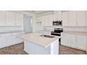 Bright kitchen with white cabinets, quartz countertops, stainless steel appliances, and wood-look flooring at 1745 Carnelian St, Deland, FL 32720