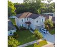 Aerial view of a charming two-story home featuring lush landscaping, a driveway, and a well-manicured lawn at 1039 Tourmaline Dr, Kissimmee, FL 34746