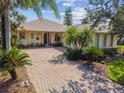 Charming single-story home with a brick driveway, lush landscaping, and tropical palm trees at 107 Belzano Pl, Poinciana, FL 34759