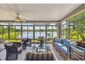Bright sunroom with panoramic lake views, tile flooring, and comfortable seating arrangement at 107 Belzano Pl, Poinciana, FL 34759