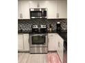 Updated kitchen featuring stainless steel appliances, white cabinets, and a stylish herringbone backsplash at 1122 Spaceport Ct, Kissimmee, FL 34741