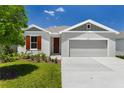 Charming single-Gathering home featuring a well-manicured lawn, gray exterior paint, and an attached two-car garage at 1749 Carnelian St, Deland, FL 32720