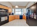 Functional kitchen with wood cabinets, black appliances, and a window overlooking the water at 2322 Queenswood Cir, Kissimmee, FL 34743