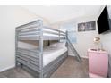 A playful bedroom showcasing a sturdy bunk bed with a ladder, alongside a pink nightstand at 3120 Paradox Cir # 302, Kissimmee, FL 34746
