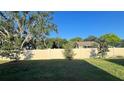 Spacious backyard featuring a white fence, green grass, and mature trees at 4357 Babbling Brook Way, Kissimmee, FL 34746
