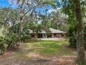 Single-story brick home with a large front yard and mature trees, offering a serene and private setting at 6340 Nelms E Rd, Lakeland, FL 33811