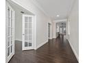 Hallway featuring hardwood floors, white walls, and glass doors leading to the office at 8374 Bowden Way, Windermere, FL 34786