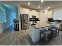 Bright kitchen showcasing an island with seating, stainless steel appliances, and wood-look flooring at 11312 Listening Dr, Orlando, FL 32832