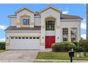 Charming two-story home featuring a red door, neutral stucco exterior, and an attached two car garage at 107 Troon Cir, Davenport, FL 33897