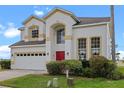 Charming two-story home featuring a red door, neutral stucco exterior, and an attached two car garage at 107 Troon Cir, Davenport, FL 33897