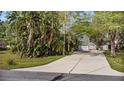 Inviting home exterior with lush tropical plants, mature trees, and a long driveway at 13959 Marine Dr, Orlando, FL 32832