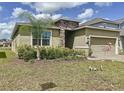 Charming home featuring a stone facade, neutral paint, manicured landscaping, and a two-car garage at 195 Preston Ave, Davenport, FL 33837