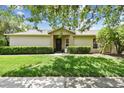 Well-manicured lawn complements the neutral exterior of this home, framed by lush greenery at 223 Bell Tower W Xing, Poinciana, FL 34759