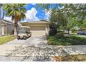Inviting home featuring a paved driveway leading to a two-car garage and a charming golf cart at 223 Bell Tower W Xing, Poinciana, FL 34759