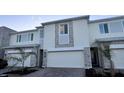 View of a well kept townhome with gray brick features, white garage door, and green plants at 312 Nine Iron Dr, Davenport, FL 33896