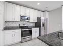 Stylish kitchen featuring stainless steel appliances, granite countertops, and white cabinetry at 3470 Beau Rd, Kissimmee, FL 34746
