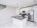 Bright kitchen features an island, white cabinets, stainless steel appliances, and modern lighting at 3470 Beau Rd, Kissimmee, FL 34746
