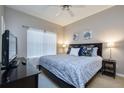 Cozy bedroom with a blue patterned comforter, ceiling fan, and a large window at 8971 Candy Palm Rd, Kissimmee, FL 34747