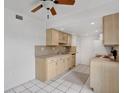 Cozy kitchen featuring light wood cabinets, tile backsplash, and modern appliances at 1038 Plantation Dr # D9, Kissimmee, FL 34741