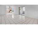 Spacious living area featuring tile floors, sliding glass doors, and a kitchen in the background at 1038 Plantation Dr # D9, Kissimmee, FL 34741